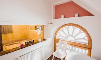 A bright and inviting room with a round window and minimalist furniture. The warm color tones create a cozy atmosphere.