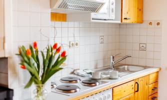 A bright kitchen with wooden cabinets and a modern stove. Fresh tulips are in a vase on the countertop.