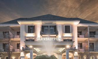 An elegant hotel with a beautifully illuminated facade. In the foreground, there is a fountain and decorative plants.
