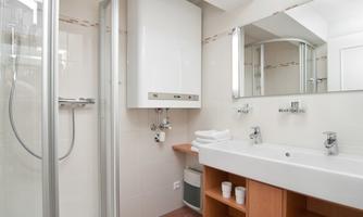 A modern bathroom with a shower and a large sink. The walls are bright, and the space feels clean and inviting.