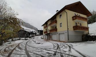 A modern building in the snow with a red roof and balconies. The surroundings are snowy and display a calm, wintry landscape.
