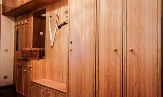 A wooden cabinet with several doors and compartments in a hallway. The floor is covered with a carpet.