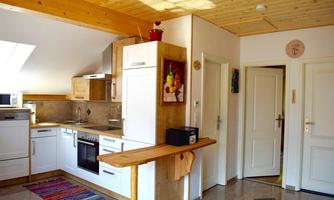 A bright kitchen with wooden elements and modern appliances. The room has large windows and a cozy atmosphere.