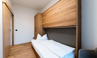 A modern room with wooden furniture and a comfortable bed. The walls are bright, creating a pleasant atmosphere.