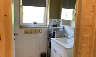 A modern bathroom with a sink and a large window. The walls are bright and the room is well-lit.