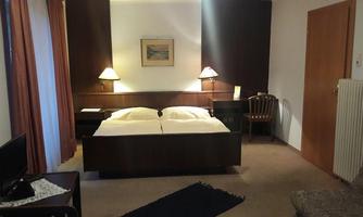 A cozy hotel room with a double bed and bedside tables. There is a desk and a chair, as well as a seating area.