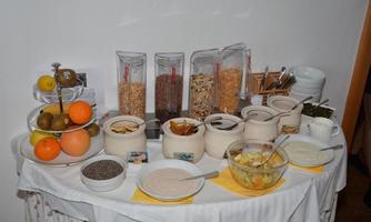 A breakfast table with various cereals and fresh fruit. There are also yogurt and dried fruits in small bowls.