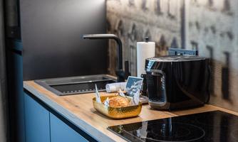 A modern kitchen with a wooden countertop and elegant appliances. On the countertop are a toaster and a bowl of snacks.