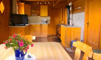 A cozy kitchen with wooden furniture and a beautiful floral arrangement on the table. The atmosphere feels bright and inviting.