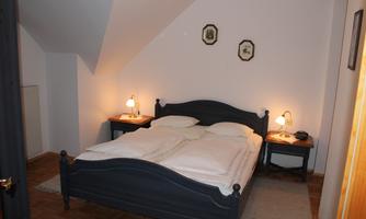 A cozy bedroom with a double bed and two nightstands. The walls are light and there is soft lighting.
