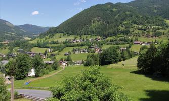 An idyllic landscape with gentle hills and green meadows. Small houses are nestled in nature, while the mountains in the background appear majestic.