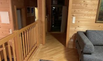 A cozy interior with wood paneling and a gray sofa. The view leads through a hallway that leads to another room.