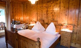 A cozy bedroom with wooden walls and two beds. Decorative figures and candles are placed on the table.
