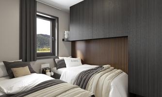 A modern bedroom with two beds and stylish textile accents. The large windows offer a view of the landscape.