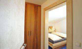 A hotel room with an open door. In the background, there is a bed and a blue carpet.