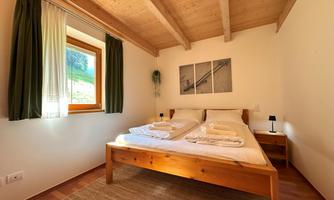 A cozy bedroom with a double bed and two pillows. Large windows provide bright light and a relaxed atmosphere.