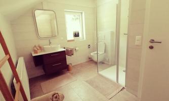 A modern bathroom with a glass shower and a sink. Bright walls and natural light sources create an inviting atmosphere.