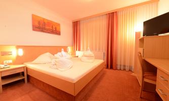A cozy hotel room with a double bed and modern furniture. Large windows let in plenty of daylight.