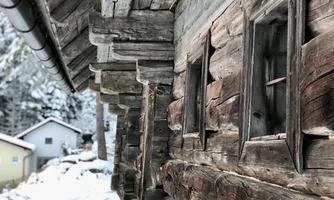 A traditional wooden house in a snowy landscape. The windows and the wooden structure are clearly visible.