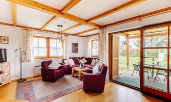 A bright living room with large windows and wooden beams. Cozy red armchairs and a table invite you to relax.
