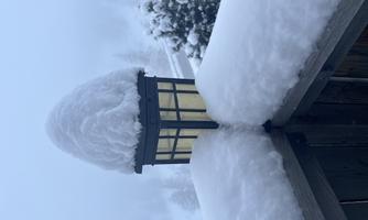 A snow-covered lantern stands on a railing. The snow covers everything and it is foggy.