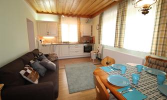 A cozy living kitchen with a bright decor and large windows. The table is set and there is a modern kitchenette.