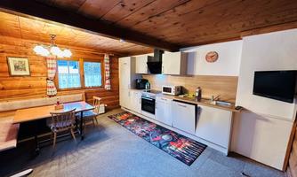 A cozy kitchen with wooden paneling and modern amenities. The room is bright and inviting, with a dining table and a seating area.