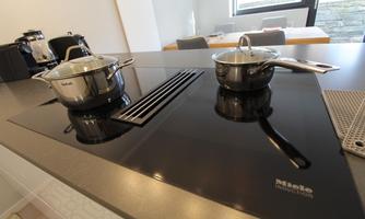 A modern kitchen with an induction cooktop. Two pots are on the cooking surface.