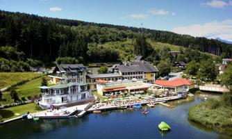 A picturesque resort by the water with recreational opportunities. Surrounded by green forests and blue skies.