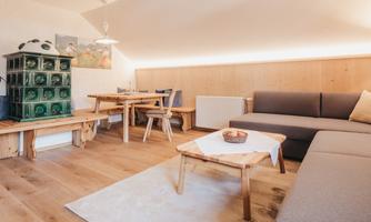 A cozy living space with wooden flooring. The room is bright and modern, featuring a sofa area and a dining nook.