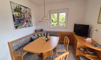 An inviting dining area with a round table and colorful chairs. The room is bright and features a large window with a view outside.