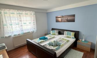 A well-decorated bedroom with a double bed and modern accessories. The walls are light blue, and the decor feels cozy and inviting.