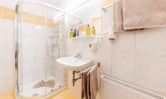 A modern bathroom with a shower and a sink. Towels and toiletries are neatly arranged.