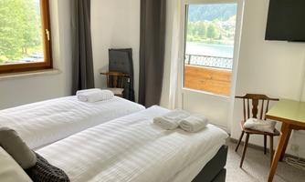 A bright room with two single beds and fresh towels. The view from the window offers a beautiful glimpse of nature.