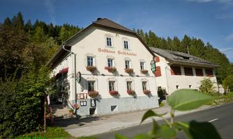 A charming inn with blooming windows and an inviting entrance. Surrounded by trees and the quiet landscape, it feels cozy and welcoming.