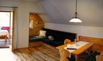 A cozy apartment with wood paneling and a dining area. The light streams in through a window, creating an inviting atmosphere.