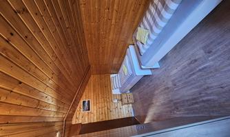 A cozy bedroom with wooden walls and two single beds. The room has a warm, inviting ambiance.