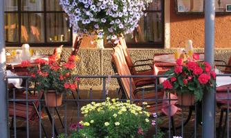 A decorative courtyard with colorful flower arrangements. In the background, tables and chairs for guests can be seen.