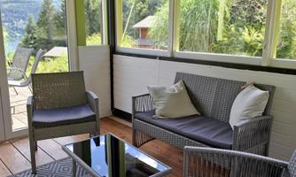 A cozy lounge with modern furniture and large windows. The room has a view of the green landscape.