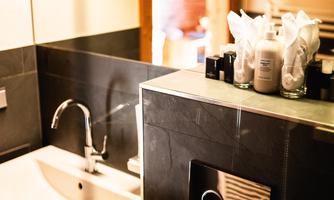 A modern bathroom with a sink and elegant care products. The design is simple and appealing, with warm light in the background.