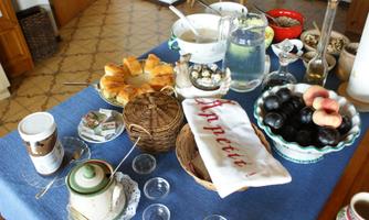 A festively set table with a variety of foods and drinks. There are pastries, fruit, and a carafe of water, all on a blue tablecloth.