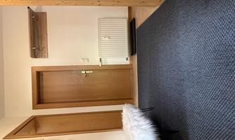 An inviting hallway with a carpet and a white bench. Adjacent doors and a wooden wardrobe give the room warmth.