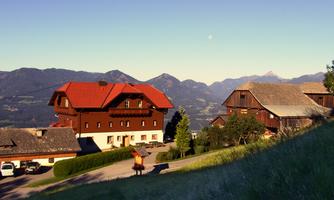 A picturesque mountain village with traditional wooden farmers' houses and red roofs. In the background, impressive mountains rise under a clear sky.