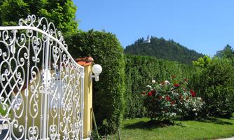 A beautiful garden with an elegant wrought iron gate. In the background, green hills and trees can be seen.