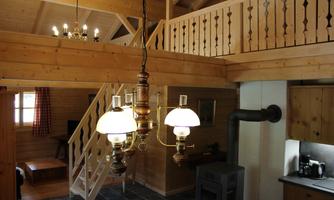A cozy wooden apartment with an open staircase and a fireplace. The decor consists of natural materials and warm light.