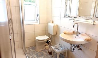 A modern bathroom with a shower, a sink, and a toilet. The floor is designed with retro tiles.