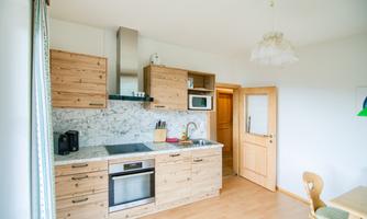 A modern kitchen with wooden furniture and bright interior. It includes a stove, a sink, and a window for natural light.
