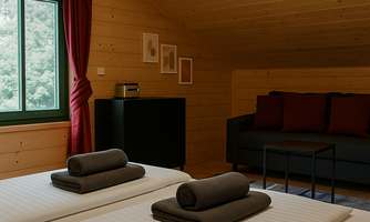 A cozy bedroom with wood paneling and two beds. Large windows with red curtains let in plenty of light.