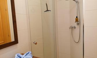 A modern bathroom with a glass shower. A blue towel is lying on the wooden table.