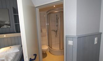 A bathroom with a shower, toilet, and sink. The room has bright tiles and a modern atmosphere.